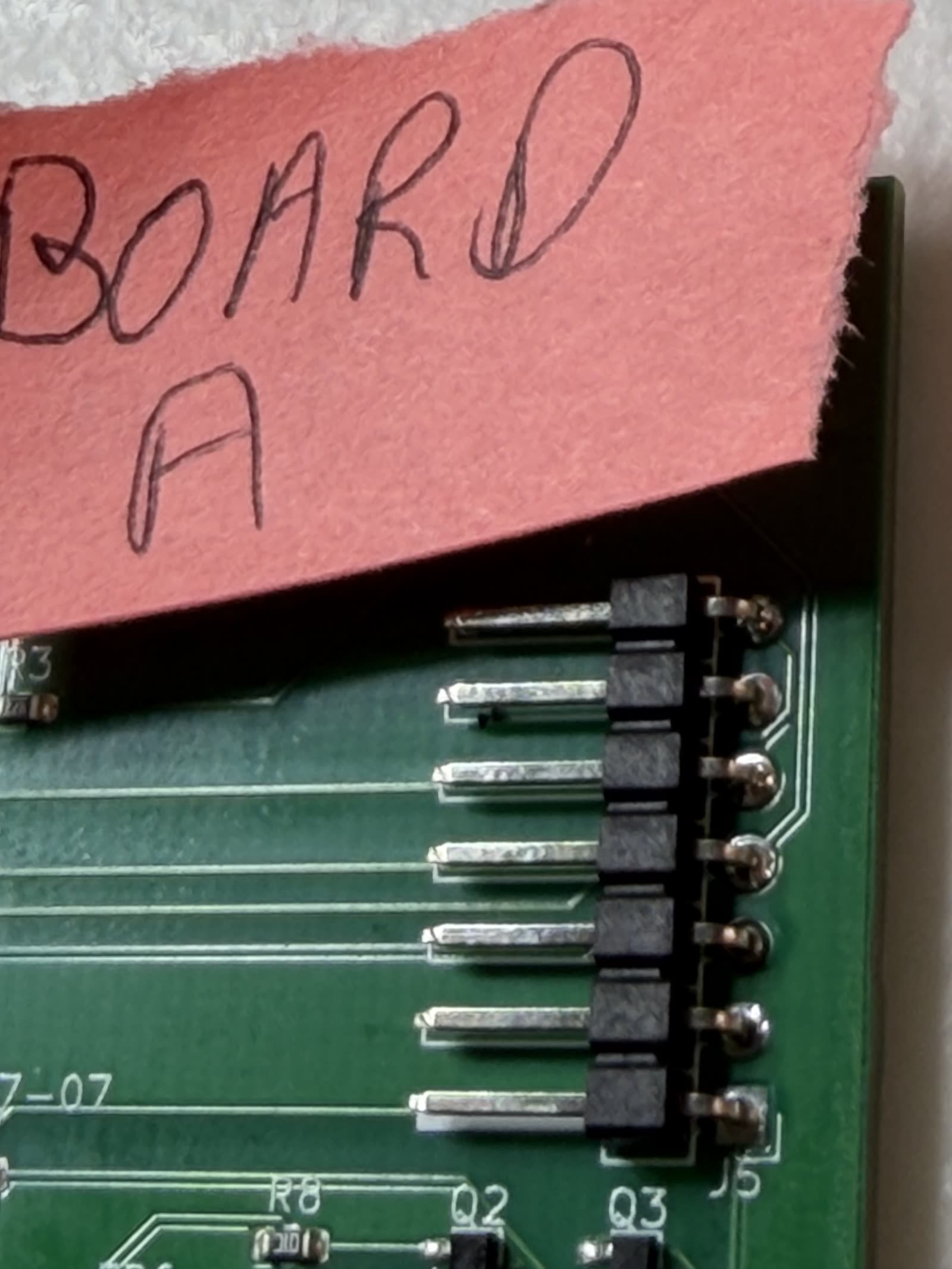 Close-up of the seven-pin right-angle J5 display header on Board A, several pins showing dull balls of solder that never spread onto the pads