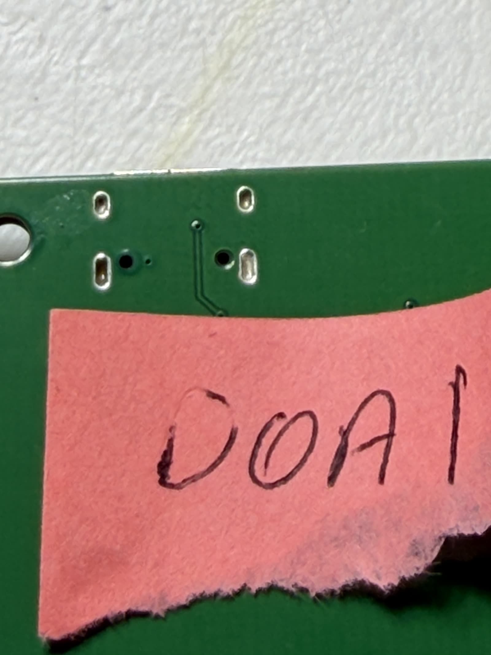 The underside of a dead board at the USB-C connector, showing the plated through-holes for the connector's shell tabs with flat, barely-wetted solder and no visible fillet