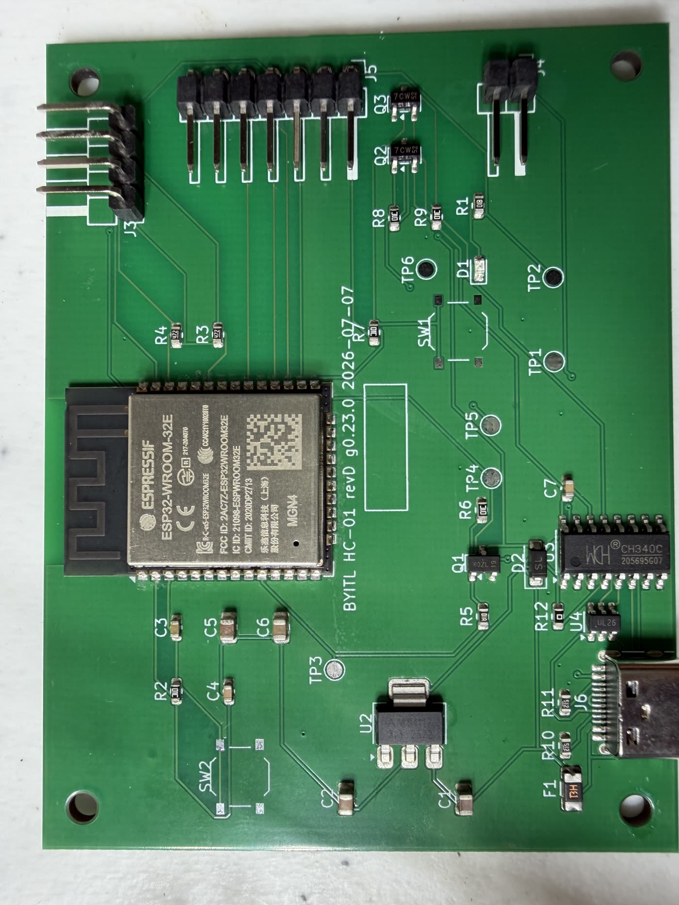The bare HC-01 rev D circuit board, green, with an ESP32-WROOM-32E module, a CH340C chip, a USB-C connector, and several pin headers