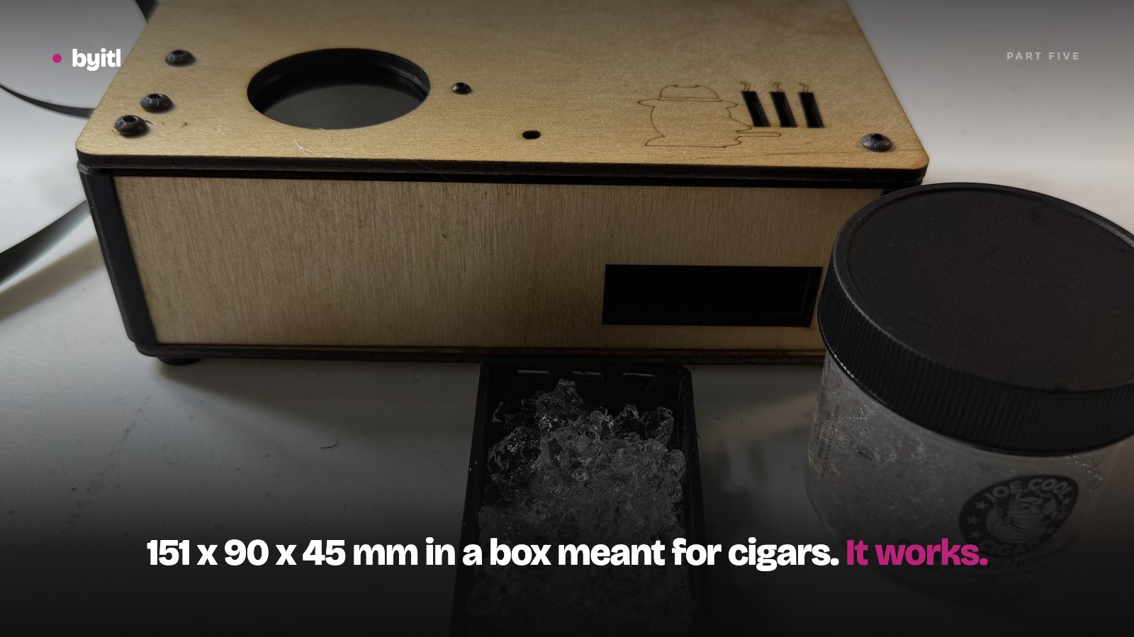 The assembled HC-01 humidor controller in its birch plywood case, lid engraved with the byitl cigar mark, beside its printed bead drawer full of humidity gel and the jar the gel came from