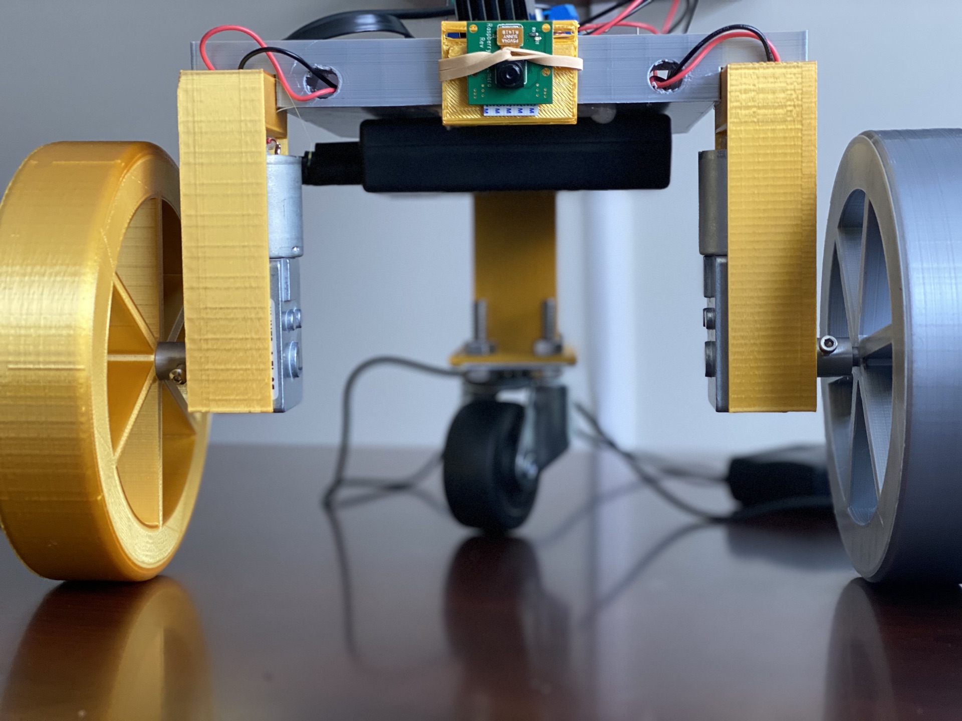 First iteration — three-wheel chassis with the Raspberry Pi camera module rubber-banded on top.