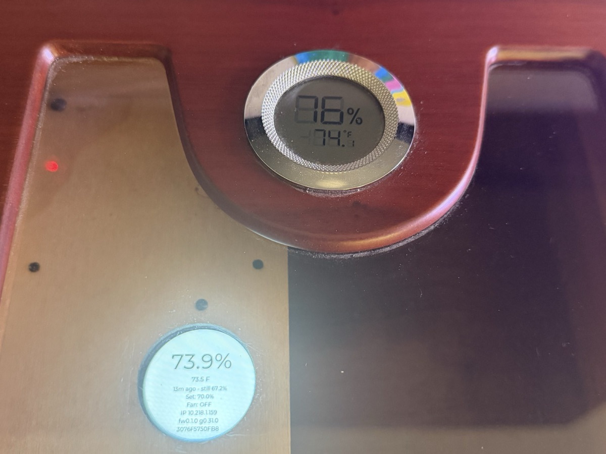 The HC-01 display reading 73.9% inside a humidor, next to the humidor’s own analog hygrometer